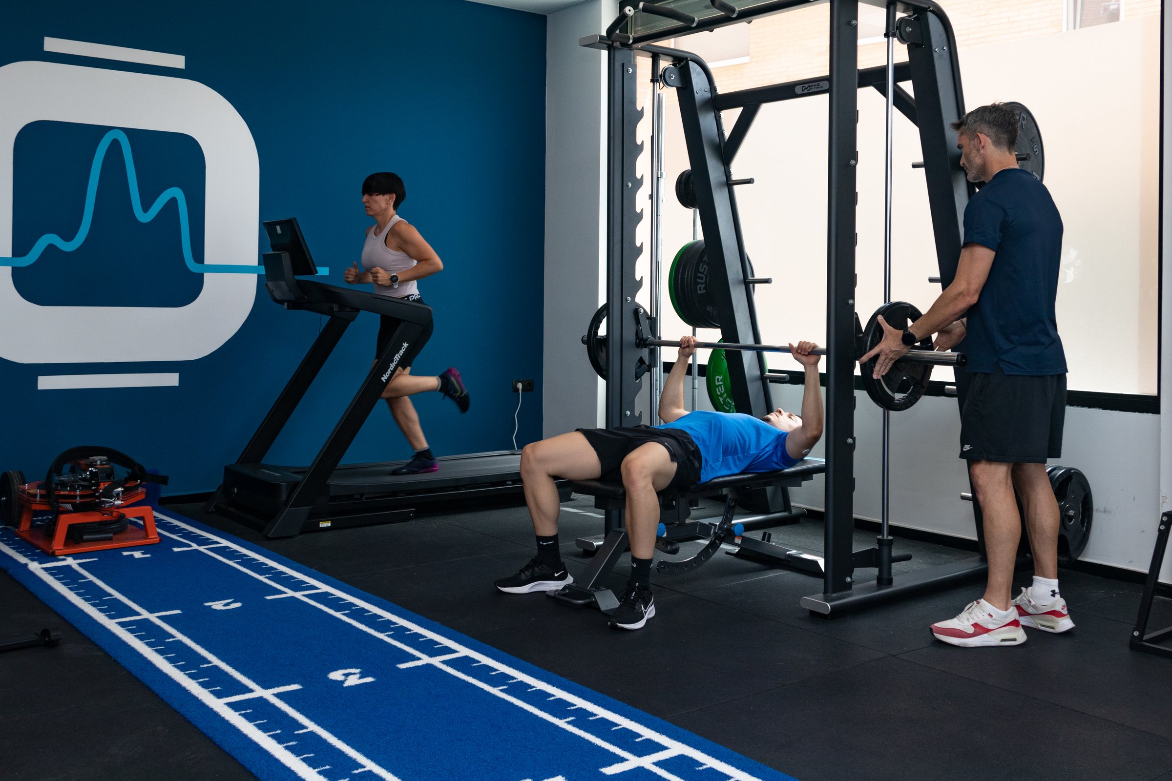 Entrenamiento deportivo en sala con cinta y banco de fuerza
